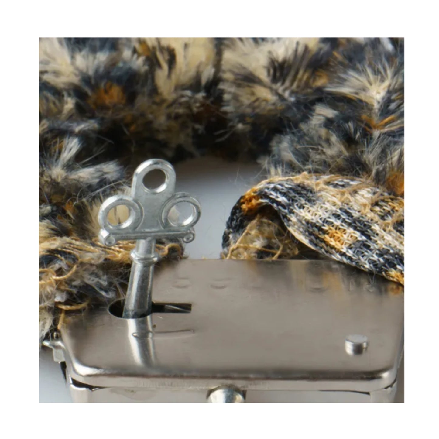 Close-up of handcuff key beside leopard plush cuff