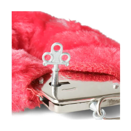 Close-up of handcuff key beside red plush cuff